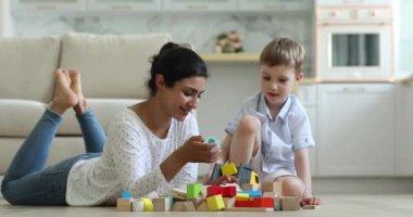 Hintli bebek bakıcısı küçük beyaz çocukla tahta küplerle oynuyor.