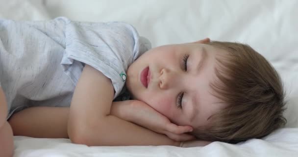 Close up kleine jongen slapen op wit vers beddengoed — Stockvideo