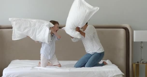 Felice indiano bambinaia giocare cuscino lotta con poco caucasico ragazzo — Video Stock