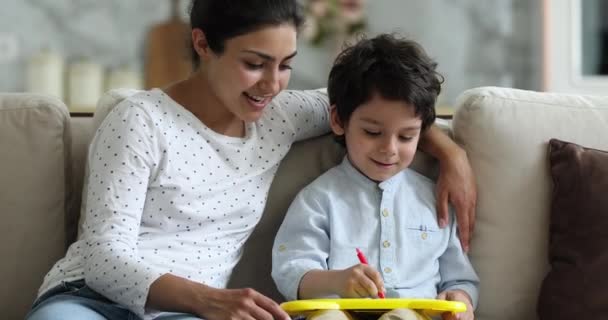 Маленький индийский мальчик и мать рисуют на магнитной стираемой доске — стоковое видео