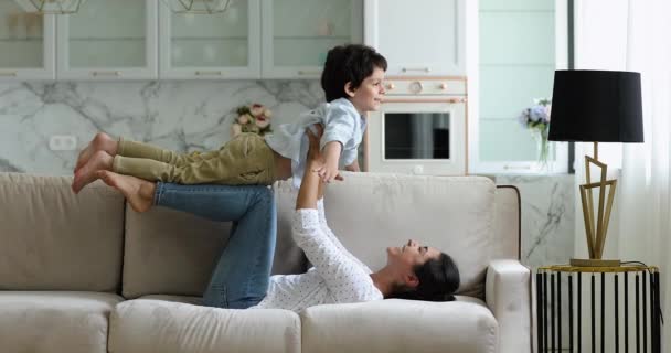 Mère indienne couchée sur le canapé soulève sur les bras petit fils — Video