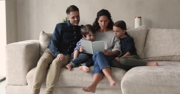 Caring young parents reading book to kids. — Video