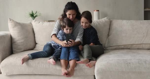 Caring young hispanic mother using cellphone with little children. — Stock Video