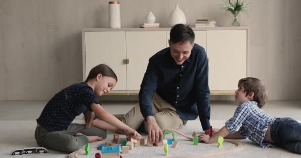 Feliz jovem pai brincando de brinquedos com crianças pequenas. — Vídeo de Stock