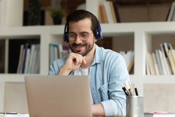 Smiling guy wear headphones watch videos on laptop — Stock Photo, Image