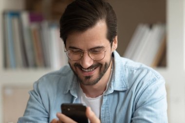 Cep telefonundan mesaj okuyan adam iyi haberler almaktan memnun.