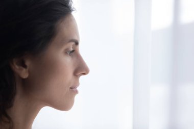 Pencerenin yanında dikilen üzgün İspanyol kadının yakın çekim yüzü.