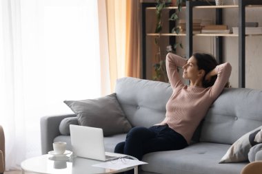 Huzurlu kadın kanepede dinleniyor. Pencereden dışarı bakıyor.