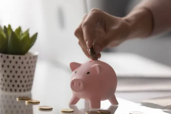 Close up female fingers put coin into pink piggybank — Stock Photo, Image