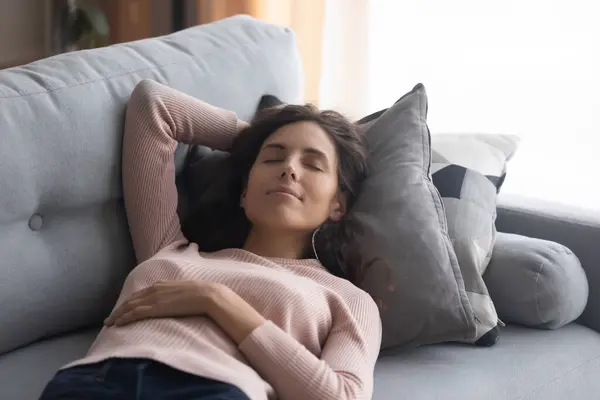 Woman lying on couch closed her eyes having day nap — Stock Photo, Image