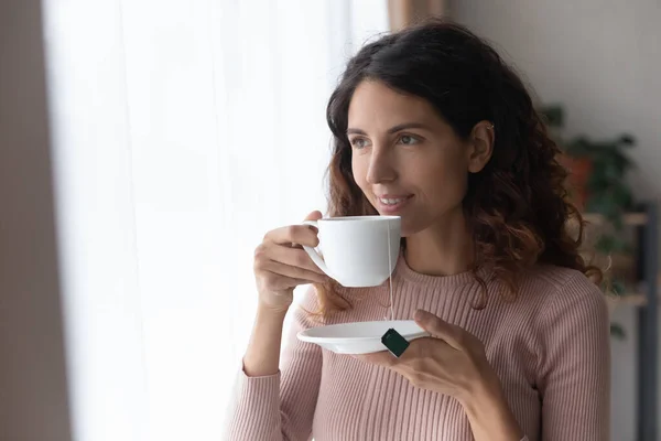 Smiling woman standing indoor with cup of tea — Stock Photo, Image