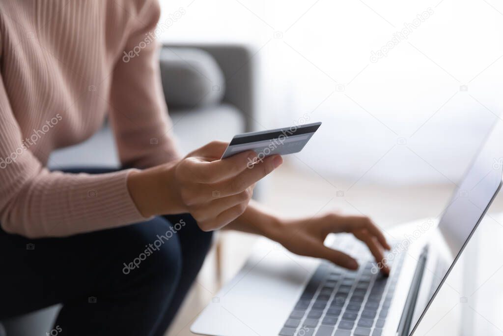 Customer buying on internet holds card using laptop close up