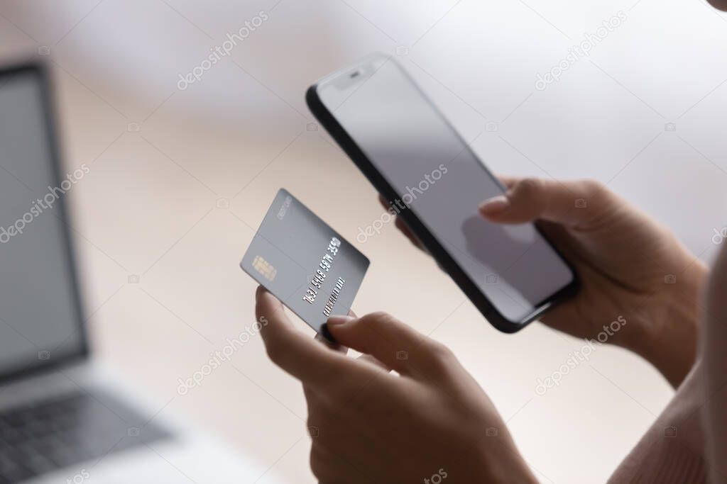 Female hands holding plastic card and cellphone purchasing goods online