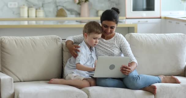 Hintli bir kadın ve küçük bir çocuk dizüstü bilgisayarla kanepede oturuyor. — Stok video