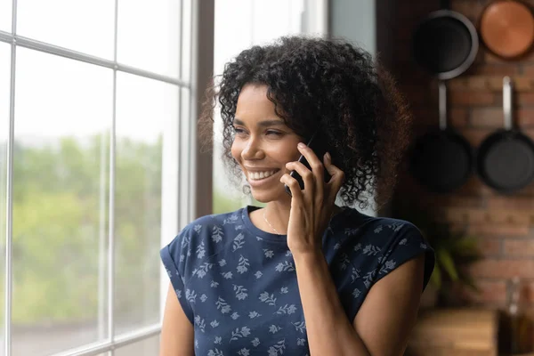 Happy thoughtful millennial Black mixed race woman making telephone call — Stock Photo, Image