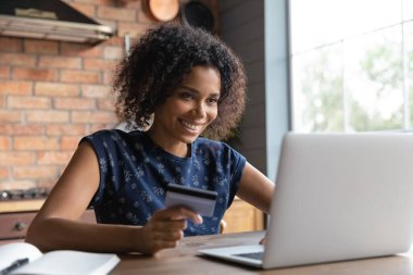 Diz üstü bilgisayar ve kredi kartı kullanan yeni nesil bayan alışverişçi.