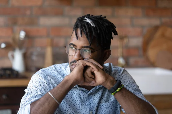 Thoughtful millennial African American man looking at window away