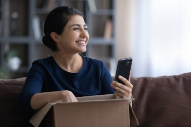 Mutlu Hintli kadın cep telefonundan alışveriş yapıyor.