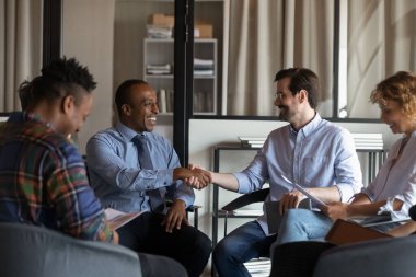 Toplantıda gülümseyen çok ırklı iş ortakları tokalaşması