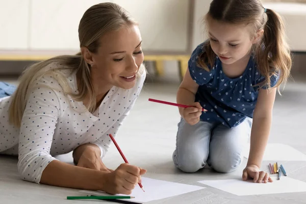 Feliz mamá enseñando a dibujar a la pequeña hija —  Fotos de Stock