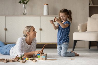 Mutlu anne ve kız sıcak zeminde dinozorlarla oynuyor.,