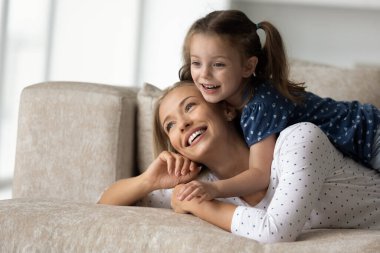 Gülen anne ve kızı evdeki kanepede dinleniyor.