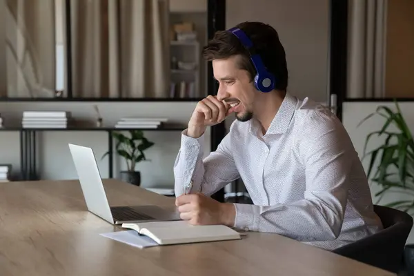 Happy male employee work distant on laptop taking notes — Stock Photo, Image