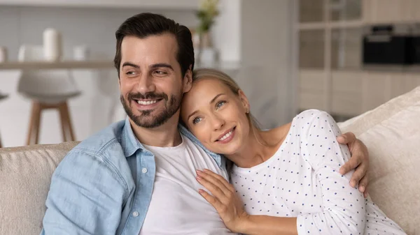 Smiling married couple relaxing and hugging on couch at home — Stock Photo, Image