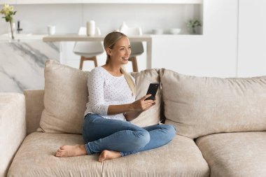 Mutlu cep telefonu kullanıcısı evdeki kanepede dinleniyor.