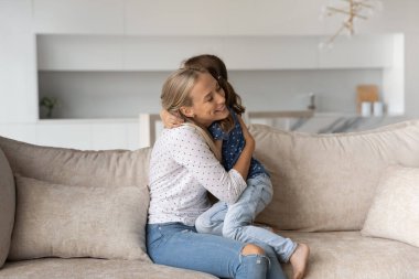 Mutlu bir anne, küçük kızı kucaklıyor ve gözleri kapalı.