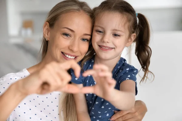 Feliz joven mamá y dulce hija chica haciendo dedo corazón —  Fotos de Stock