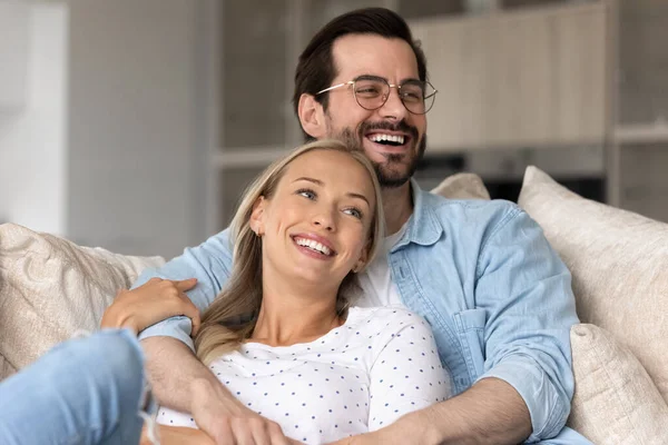 Happy joyful married couple resting and hugging on sofa — Stock Photo, Image