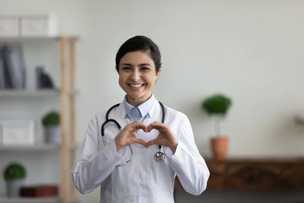 愛のシンボルを示す美しい若いインド人医師の笑顔. — ストック写真