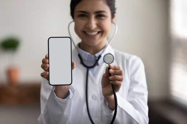 Close up young indian female cardiologist holding cellphone and stethoscope.
