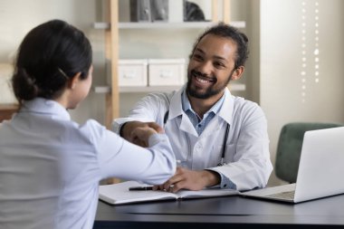 Hintli bir hastayla tokalaşan mutlu genç Afrikalı doktor..