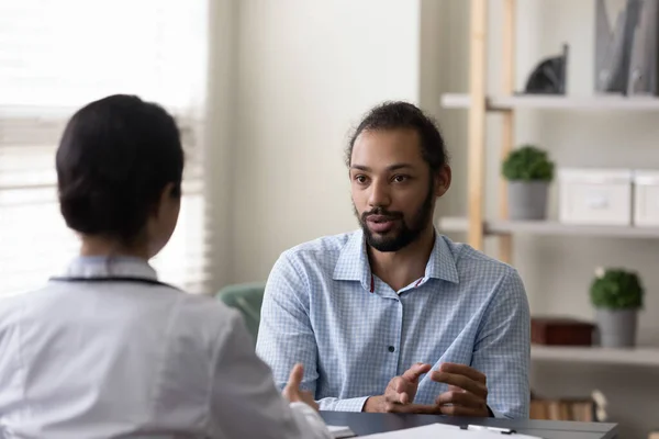 Jonge Afro-Amerikaanse patiënt bespreekt ziektebehandeling met arts. — Stockfoto
