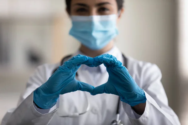 Close up millennial indian doctor showing love symbol.