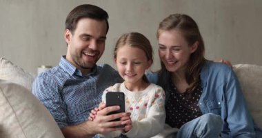 Çift ve küçük kız cep telefonuyla oyun oynuyorlar.