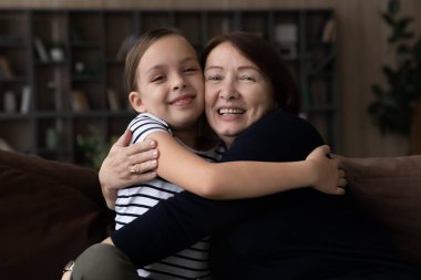 Mutlu küçük kız evde yaşlı büyükannesine sarılıyor..