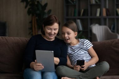 Teknolojiye bağımlı yaşlı büyükanne ve küçük çocuk aletler kullanıyor..