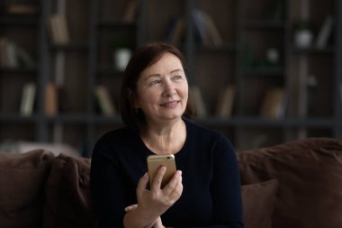 Akıllı telefonu elinde tutan yaşlı ve mutlu bir kadın..