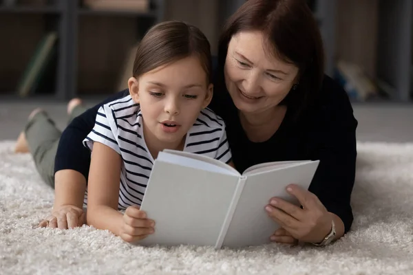 Feliz abuela mayor lectura libro con nieta. —  Fotos de Stock