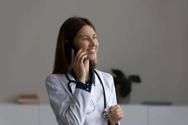 Leende ung 30-talet kvinnlig läkare som håller mobiltelefon konversation. — Stockfoto