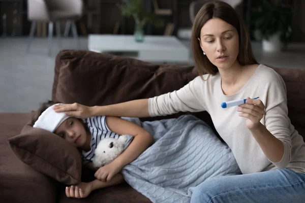 Worried young mother checking body temperature of small daughter. — Stock Photo, Image