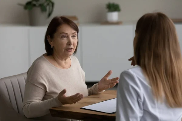 Mujer mayor feliz consultando con médico joven. — Foto de Stock