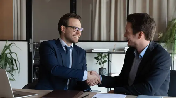 Sorrindo empresário gerente tremendo mão cliente satisfeito na reunião — Fotografia de Stock