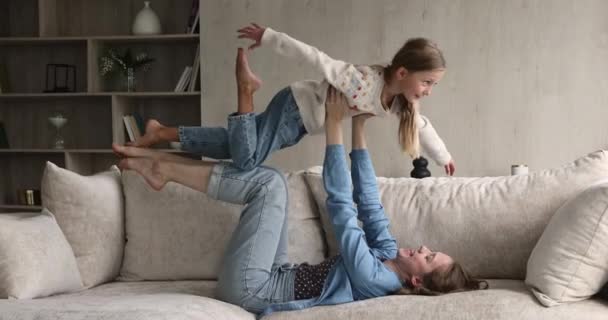 Mulher sua filhinha realizar exercício acroyoga no sofá interior — Vídeo de Stock