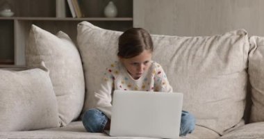 Kız kanepede dizüstü bilgisayarla oturup internet sitesini kullanarak ders çalışıyor.