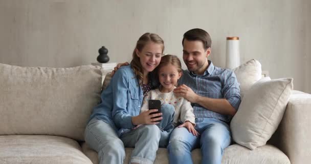 Pareja e hija se divierten utilizando la aplicación móvil en el teléfono celular — Vídeos de Stock