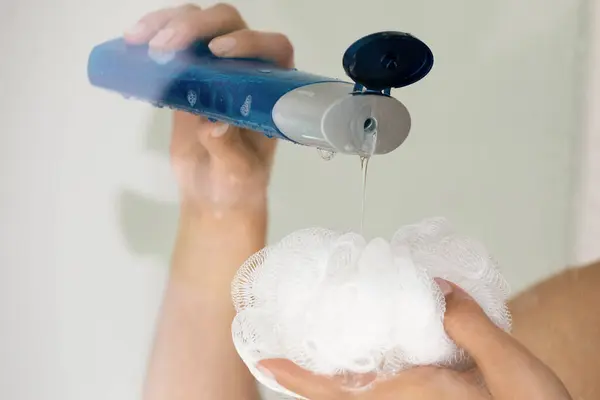 Close up young woman pouring shower gel on puff. — Stock Photo, Image